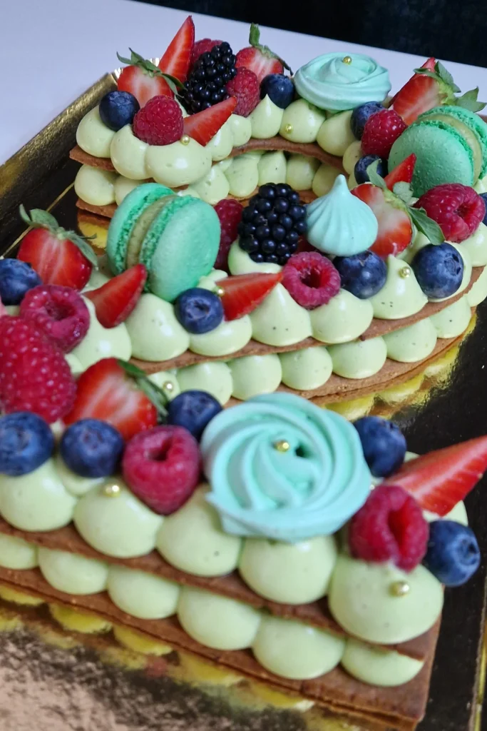 Un gâteau biscuit garnis Number cake Pistache/Fruits-rouges en forme de 2